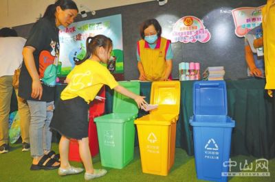 低碳主题宣传活动现场,小学生体验模拟垃圾分类游戏,并赢取奖品.